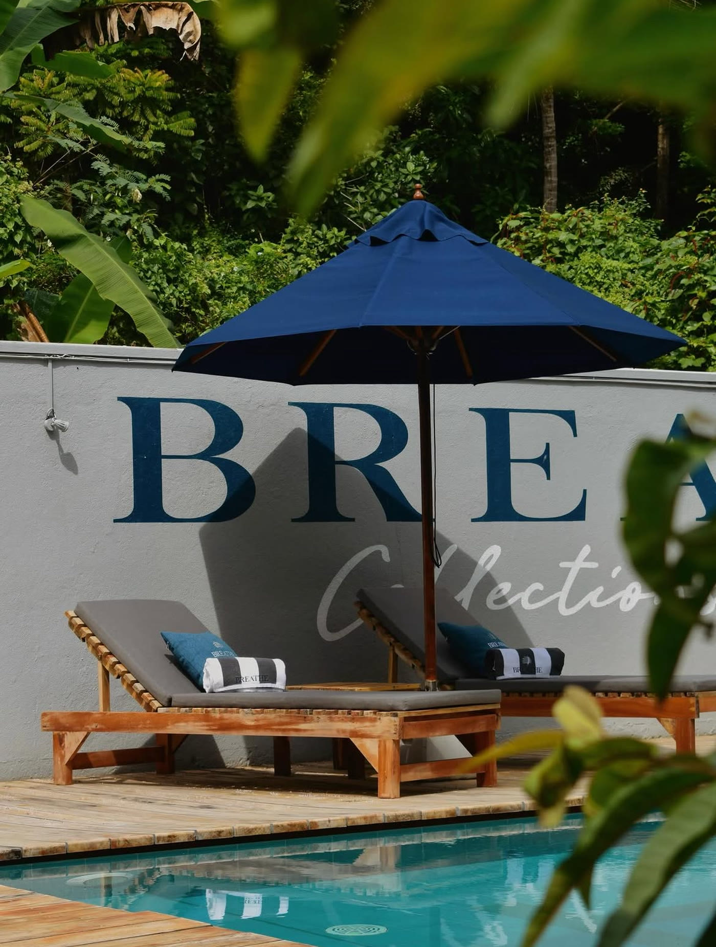 Sun loungers by the pool under the Breathe Collections mural